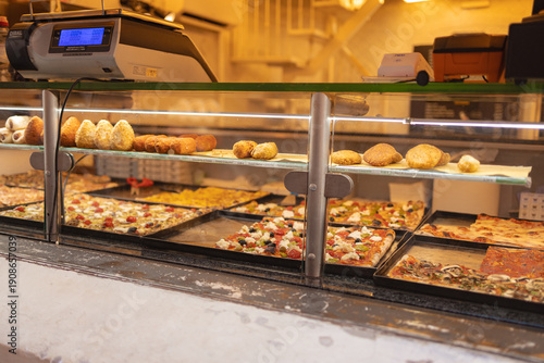 Photography Traditional Italian street food including pizza slices and fried snacks displayed in a bakery showcase in the historic center of Rome