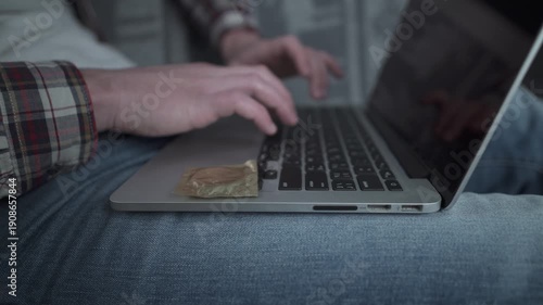 Man using laptop for online dating with a condom nearby. Concept of safe sex and protection during casual encounters. Responsible behavior and health awareness in digital age hookup culture.