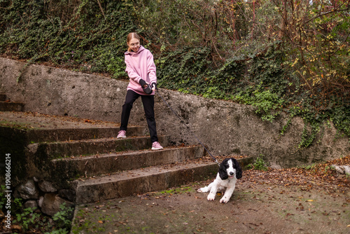 Teenage blonde Slavic girl walking a Russian spaniel dog on stone steps in Montenegro during early autumn