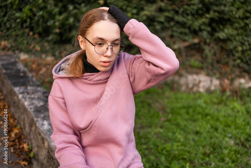 Close portrait of a teenage blonde Slavic girl in a pink hoodie outdoors in Montenegro