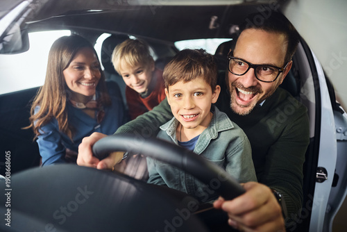 Happy family having fun while testing new car in showroom.