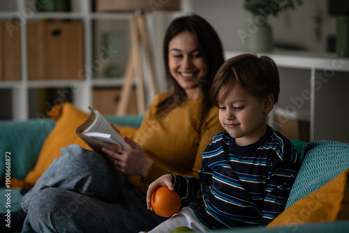 Foto Mother reading book to child on sofa