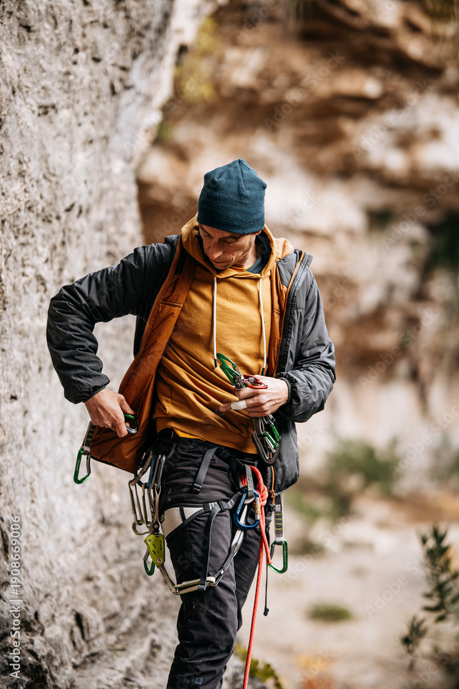 Fototapeta premium Male Rock Climber Adjusting Harness And Carabiners: Safety Gear Preparation In Golle Della Stretta Sicily Italy