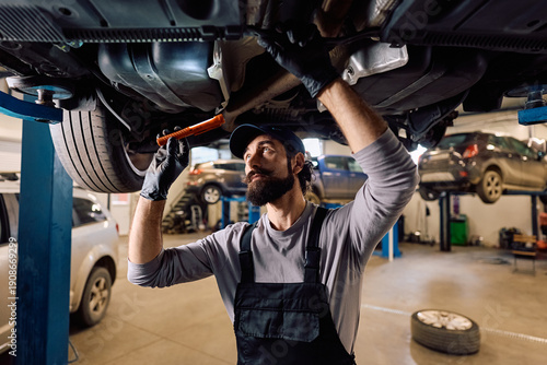 фотографія Car mechanic doing maintenance on chassis while working in garage
