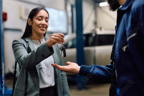 Close up of customer handing over her cay key to mechanic in workshop.
