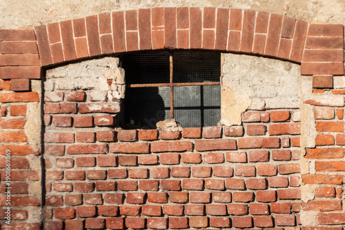Weathered brick window with arched lintel and iron crossbar, revealing layered textures and timeworn materials, perfect for architectural storytelling, heritage themes, and restoration visuals