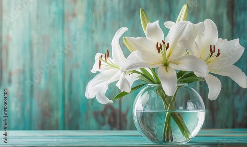 Elegant glass vase filled with fresh white lilies, placed on a teal-colored wooden table with soft natural light creating a serene floral arrangement