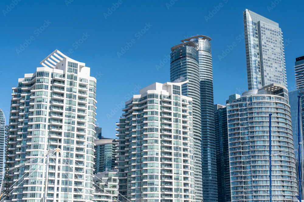Fototapeta premium Modern residential skyscrapers dominating the urban skyline of toronto, canada, under a clear blue sky, symbolizing modern architecture, urban living, and growth
