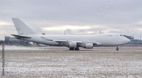 Photos Side profile of a generic white jumbo jet airplane taxiing on a snowy airport ru