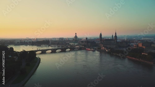 A aerial drone shot gliding from afar toward the historic city center of Dresden, captured at dawn above the River Laube