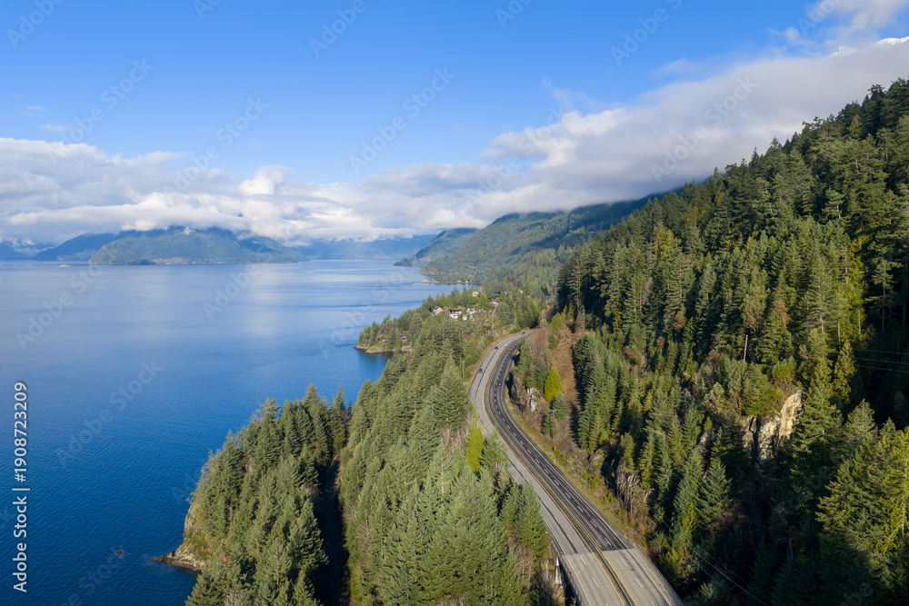Fototapeta premium Coastal Forest Road Along Sea to Sky Highway With Calm Blue Water And Mountain Backdrop