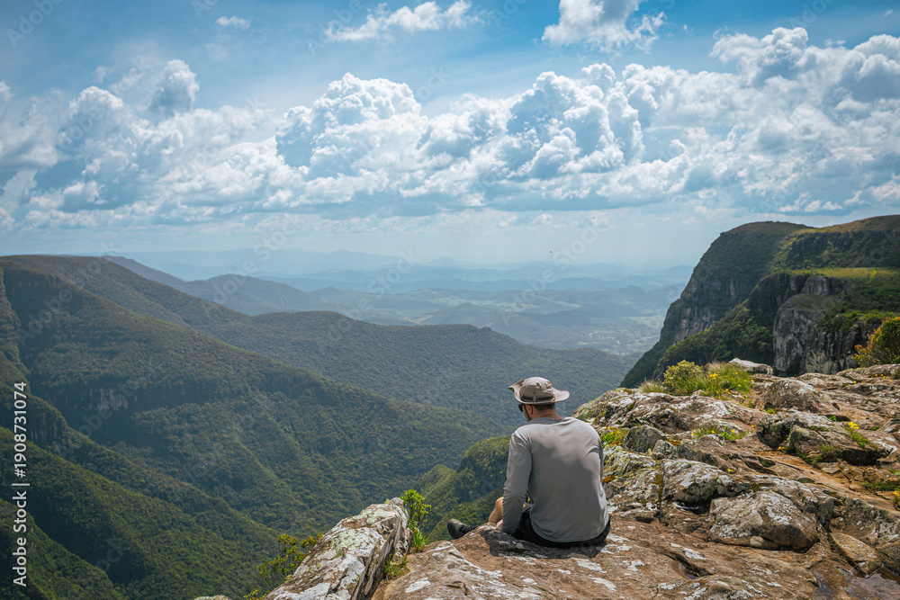 Fototapeta premium Hiker sitting on cliff overlooking Itaimbezinho Canyon in Brazil