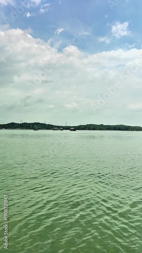 view of a green lake with a background of mountains and blue sky