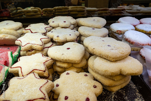 Billede på lærred A close up shot of different cookies with sugar coating and red icing stacked high in a bakery display case