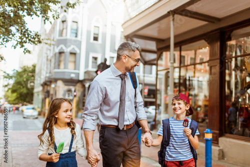 Photos Working father walking with children on downtown city street
