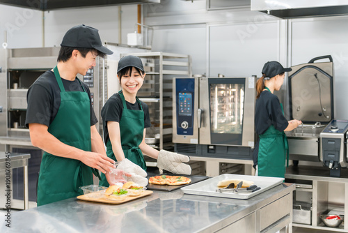 Bild auf Leinwand Men and women in uniform working in the kitchen or backyard of a restaurant