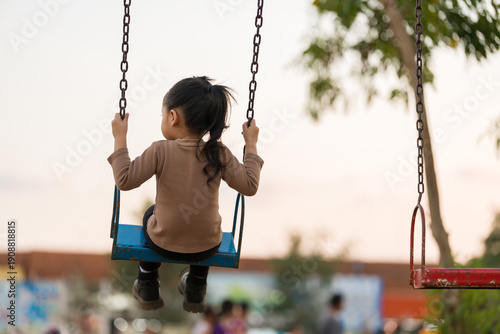 cheerful child girl playing on swing at playground