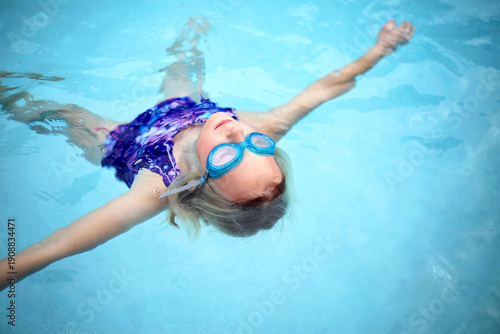 Child Relaxing and Floating in Swimming Pool Water on Her Back
