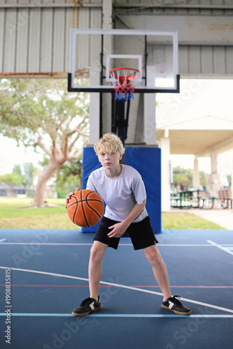 Teen Boy Playing Basketball Outside on Outdoor Court