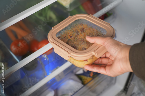 Bild auf Leinwand Hand reaches for container in refrigerator with vegetables