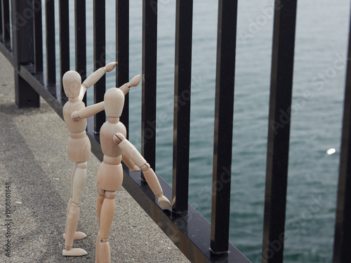 Wallpaper Mural 海岸の堤防の落下防止柵のそばに立つ二人の木製のマネキン人形の姿 Torontodigital.ca