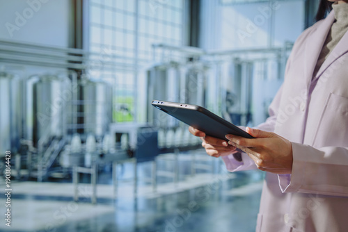 Asian young female quality control specialist holding a tablet in a modern dairy factory, approving production standards, ensuring food safety,hygiene compliance,smart manufacturing, industrial
