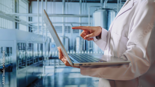 Asian young female quality control specialist holding a tablet in a modern dairy factory, approving production standards, ensuring food safety,hygiene compliance,smart manufacturing, industrial