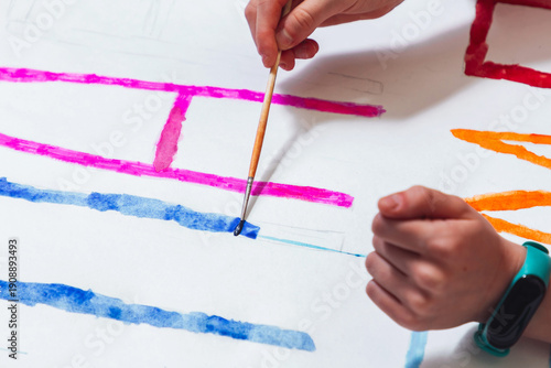 The girl's hand draws with multicolored paints