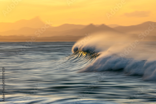 Slika na platnu Slow shutter speed photograph of a breaking ocean wave at Byron Bay, Australia, captured at sunset