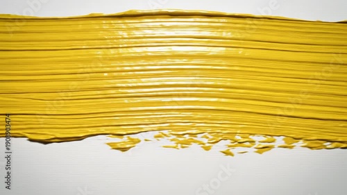 Vibrant yellow paint smear on a textured white background with thick brush strokes