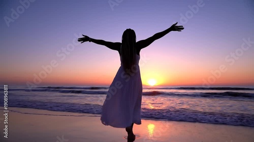 Wallpaper Mural A woman in a white dress dancing on the beach at sunset with her arms outstretched Torontodigital.ca