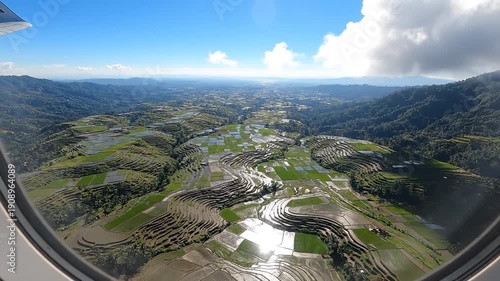 Wallpaper Mural Aerial view of terraced rice fields in a valley surrounded by mountains, with a town and blue sky in the background, seen from a plane window Torontodigital.ca