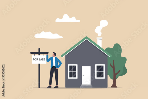 A man standing next to a for sale sign in front of a small house with a chimney and a tree.