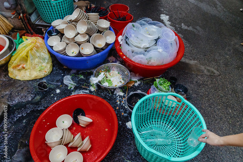 Foto Piles of used ceramic bowls, plastic plates, and food waste from a busy street food vendor in Hoan Kiem, Hanoi, Vietnam, awaiting cleanup