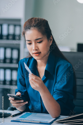 Young businesswoman is holding two credit cards with a worried expression, trying to decide which one to use to pay off her debt