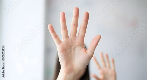 Womans hand raised with fingers extended showing a five gesture closeup