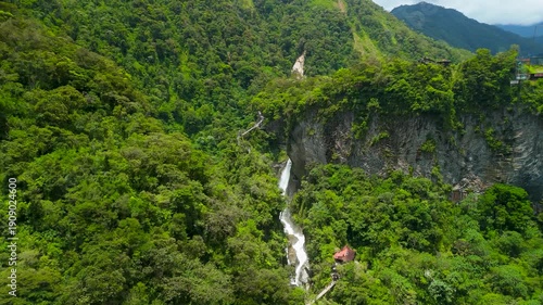 Cinematic aerial view flying toward the massive thundering plume of El Pailon del Diablo waterfall revealing the sheer power of the water and the deep rocky canyon in Ecuador