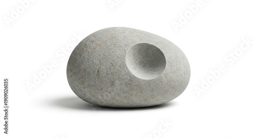 Grey stone with a circular indentation resting on a white surface with a shadow