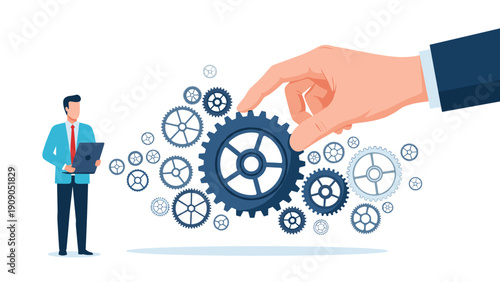 Professional businessman looking at a laptop while a giant hand manipulates large blue gears representing management and control.
