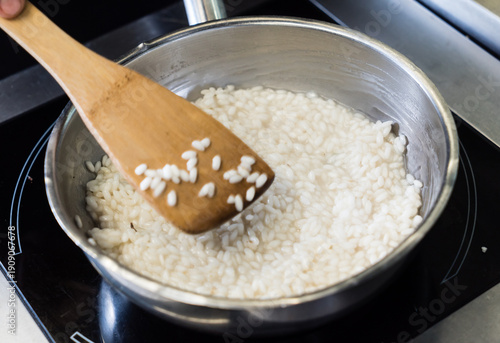 Obraz na plátne A hand stirs creamy rice gently in a pot, showcasing the art of cooking during a