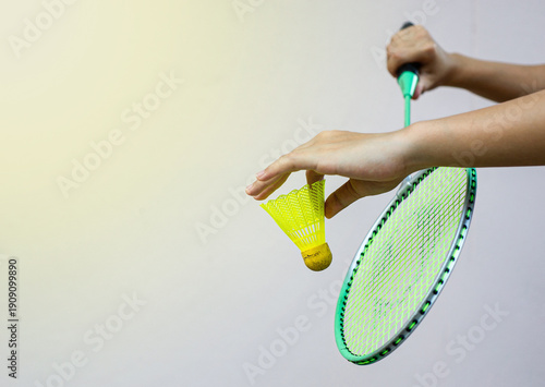The badminton player is serving the shuttlecock.
