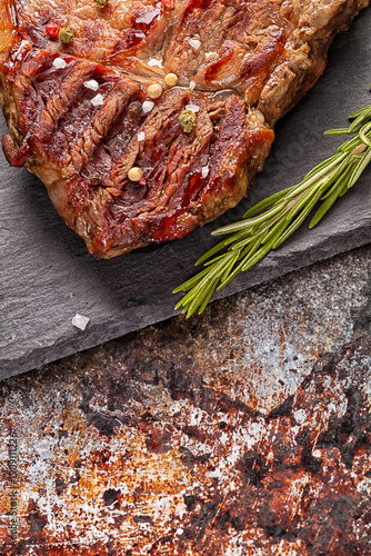 Juicy medium rare beef steak slices on ceramic board with herbs