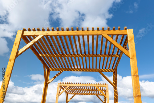 a wooden frame made of logs on the beach against a sky with clouds, part of a wooden frame building under construction to create a good infrastructure for recreation, a canopy made of planks