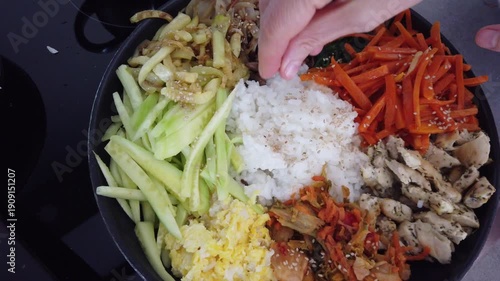 Mixing colorful vegetables and rice in a pan while cooking traditional korean bibimbap dish