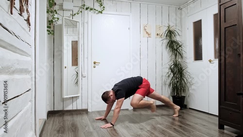 Athletic man Performs Mountain Climbers on the home Floor, Wearing a tank top and red shorts. Healthy lifestyle. Sporty person doing sport exercises. Morning routine warm-up. High quality 4k footage.