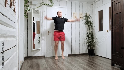 Caucasian man doing an exercise Jumping Jacks on floor at home. Fast workout. Morning warmup. Person strengthening the muscles of legs, endurance and balance. Strong sporty body. HQ 4k footage.