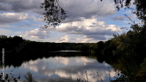 Cloudy day lakeshore landscape framed between trees with vegetation silhouette near Regensburg Germany