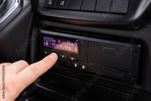 Truck driver hand pressing buttons on digital tachograph dashboard unit