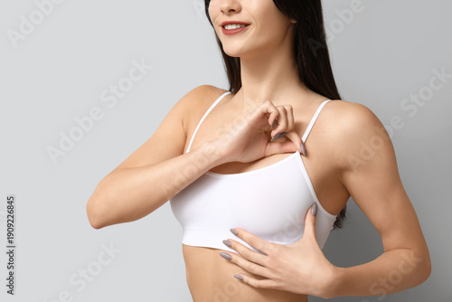 Photos Young woman checking her breast on grey background