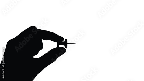 Silhouette of a hand carefully holding a push pin against a plain white background for minimalist office concept and strategy.